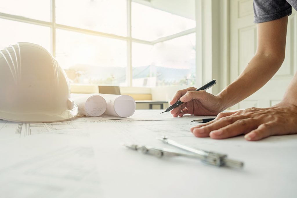 Persona trabajando sobre plano de construcción - CMH